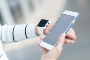 Woman wearing smartwatch and connecting to cellphone